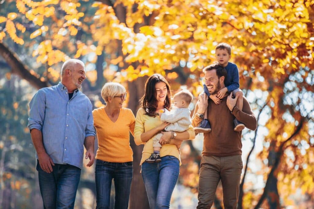 A family enjoying a leisurely stroll in the park during the autumn season, surrounded by colorful foliage. - Getting life insurance coverage for stay-at-home parents