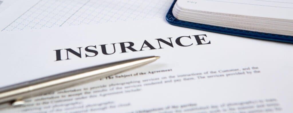 A sheet of paper detailing insurance information with a pen placed beside it for signing