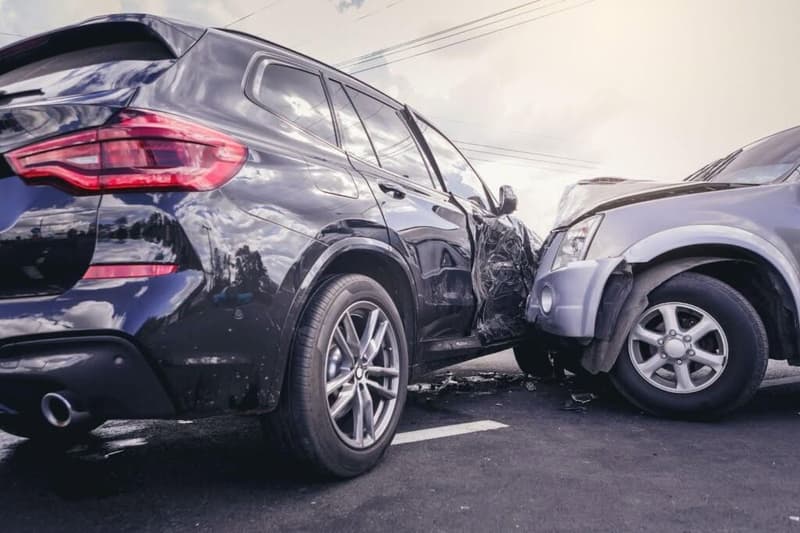 A damaged car on the road shows signs of a collision